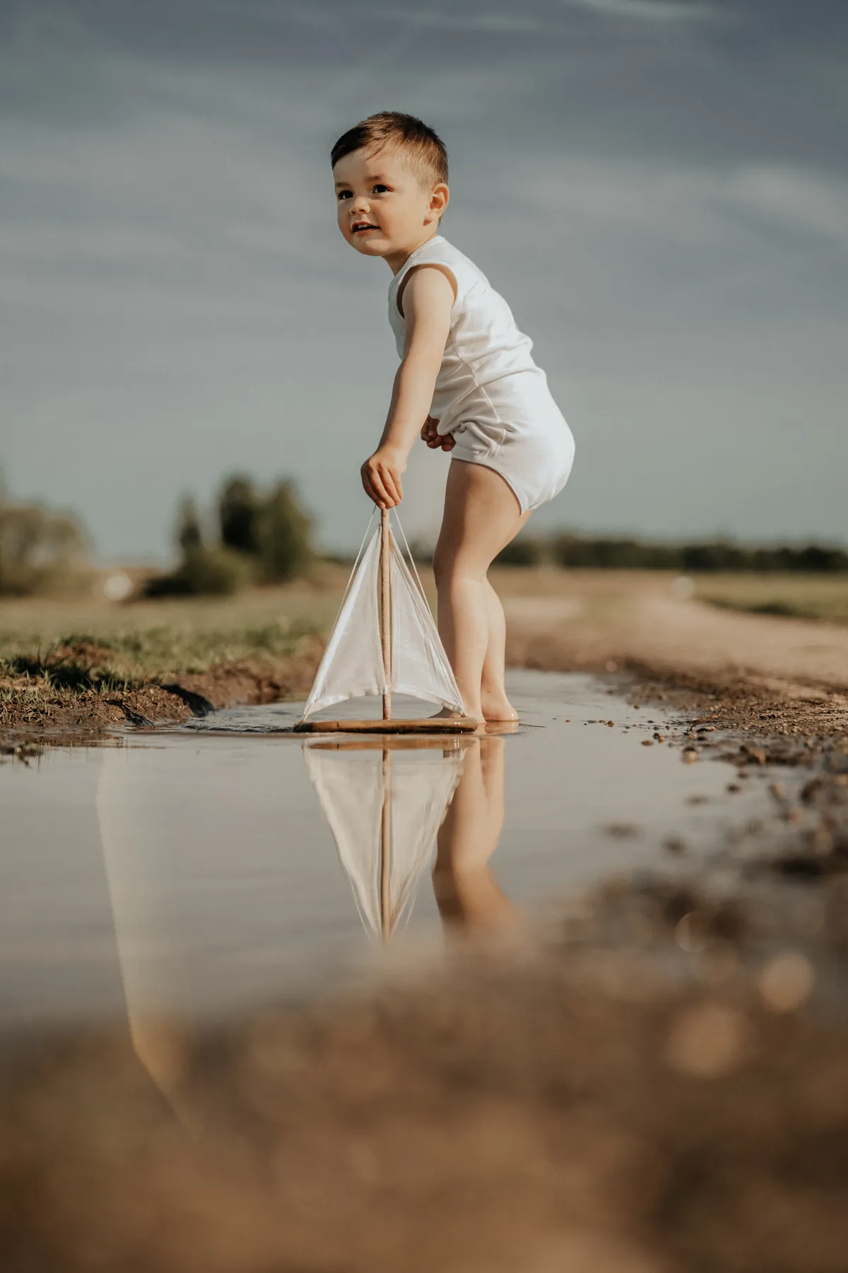 Junge mit Segelboot am Wasser